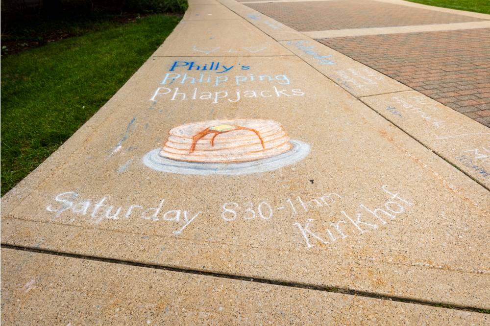 Sidewalk chalk art of a stack of pancakes promoting Family Weekend Pancake Breakfast.